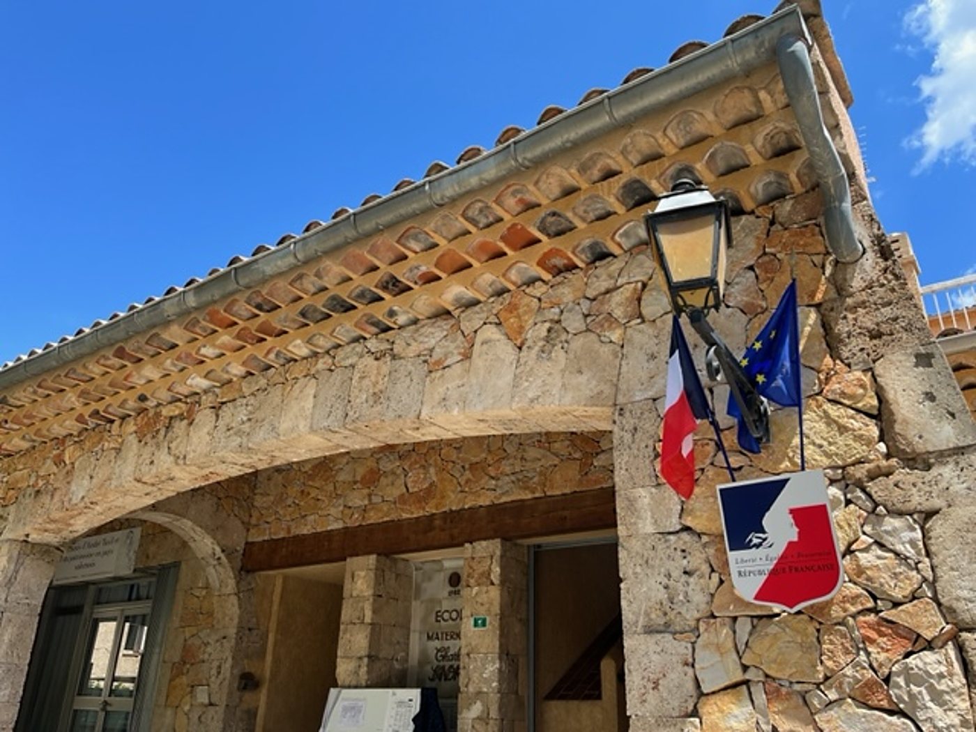 Façade en pierre d'une école avec drapeaux français et européen